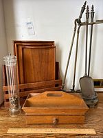 Photo showing full set including metal fireplace tools with stand at right, 3 nesting wood trays in wooden holder behind, wood caddy with drawer front and center, wood mail holder at back, and clear acrylic pepper grinder on left.