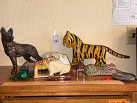 Two photos showing the full collection of exotic animal figurines and carvings on a wooden surface.