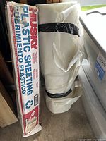 Husky boxed black plastic sheeting roll beside taped clear roll