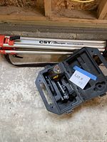 Laser level case open with unit, tripod folded alongside