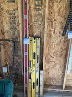 Four visible levels leaning against wall with lot tag