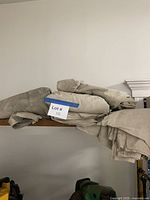 Stack of folded beige canvas drop cloths on shelf