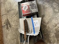 Lot overview showing sawhorses stacked with boxed air hammer, dustpan, brush
