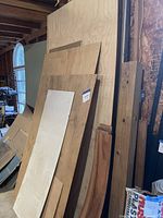 Stack of plywood, luan, drywall and boards leaning against wall