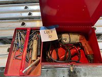 Open red toolbox showing Milwaukee hammer drill, cord and tray with bits and screws