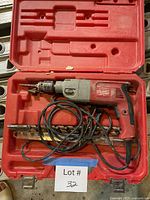 Open red case with Milwaukee hammer drill, bits, cord visible