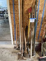 group of long-handled tools leaning against wall