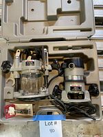 Open case showing router motor in fixed base, plunge base, wrenches, packaged bit