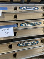 Stacked Werner aluminum extension ladders showing side rails with logos