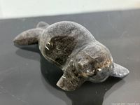 Close-up front angle of polished stone seal sculpture showing detailed flippers, rounded body, and face.