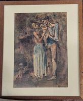 Framed print showing a family group with two adults holding a child, in muted colors with wooden frame and beige mat.