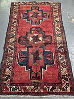 Full view of the Persian wool rug showing entire geometric medallion design, border, and fringes