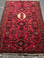 Full view of the rectangular Persian wool rug with a rich red background and detailed geometric and floral patterns.