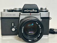 Front view of Minolta XE-5 camera with attached MD 50mm f/1.4 lens showing lens glass and camera branding