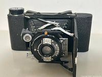 Front view of the vintage folding camera open, showing lens plate and bellows.