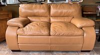 Front view of caramel pleather loveseat sofa showing cushions and armrests.