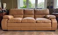 Front view of caramel pleather 3-seat sofa showing three cushions and wide padded arms.