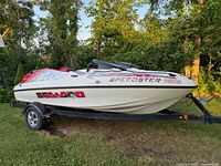 Side profile of white and red Seadoo Speedster jetboat mounted on a black Shorelander trailer