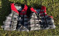 Pair of Seadoo life jackets laid flat showing front with adjustable straps and red/black/grey color scheme.