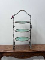 Photo of a 3-tier kitchen utility stand with intricate metal frame and teal plates.