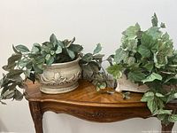Two decorative planters placed on a wooden surface, displaying their floral design and vintage look.