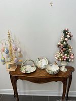 Set of three Fitz and Floyd ceramic Spring/Easter themed pieces on wooden table including a decorative bowl, plate, and handled tray, displayed with Easter decorations.
