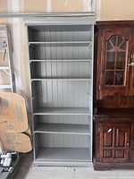 Front view of grey IKEA bookshelf showing six shelves and minor surface chips.