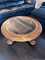 Round oak coffee table with glass top viewed from above showing wood grain and glass insert.