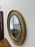 Side view of the round mirror showing the vintage ornate gold frame with detailed patterns and texture.