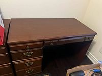 Left side drawers close up showing three ornate metal handles on large drawers and smaller drawer with simple metal knob on top right