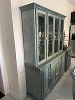 Full view of vintage oak buffet with distressed blue-green finish showing both buffet and upper hutch with glass doors and shelving.