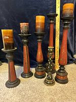 Group shot of six candle holders with candles showing varying heights and styles