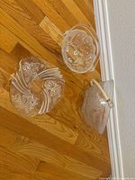 Three holiday-themed clear glass pieces on floor