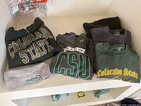 Folded hoodie, three T-shirts and beanie on shelf
