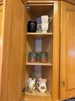 Full cabinet view showing mugs, painted glasses, teaspoon container, wine opener