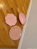 All three pink ceramic dishes on wood floor