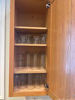 Cabinet with three shelves of assorted clear glass tumblers