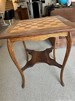 Full view of wooden checkerboard table showing legs, apron and shelf