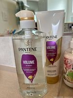 Pantene shampoo and conditioner alongside floral pump lotion bottle
