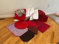 Pile of assorted table linens showing all items together including tablecloths, runners, placemats, napkins