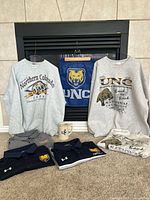 Lot overview showing sweatshirts, polos, flag, mug