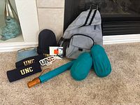 Group shot of all items including backpack, beanie, headbands, visor, umbrella, teal pouches, stickers, noise stick