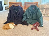 Two jackets on hangers with gloves, mittens and scarves arranged in front