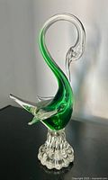 Full view of green and clear glass bird sculpture on pedestal base