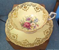 teacup nested in saucer showing interior floral design and gold scroll trim