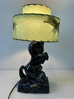 Full view of lamp illuminated showing horse base and glowing double-tier shade