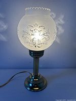 Lamp lit showing full view of metal base and frosted etched shade