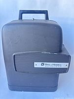 Front view of Bell & Howell Autoload projector in closed hard case showing nameplate and handle