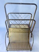 Full view of brass tone metal magazine rack showing three compartments and lattice panels
