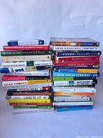 Two tall stacks of assorted hardcover and paperback non-fiction/self-help books, spines facing forward